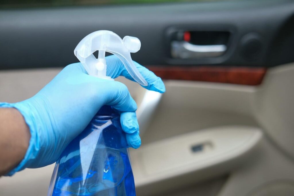 person spraying air freshener in the car